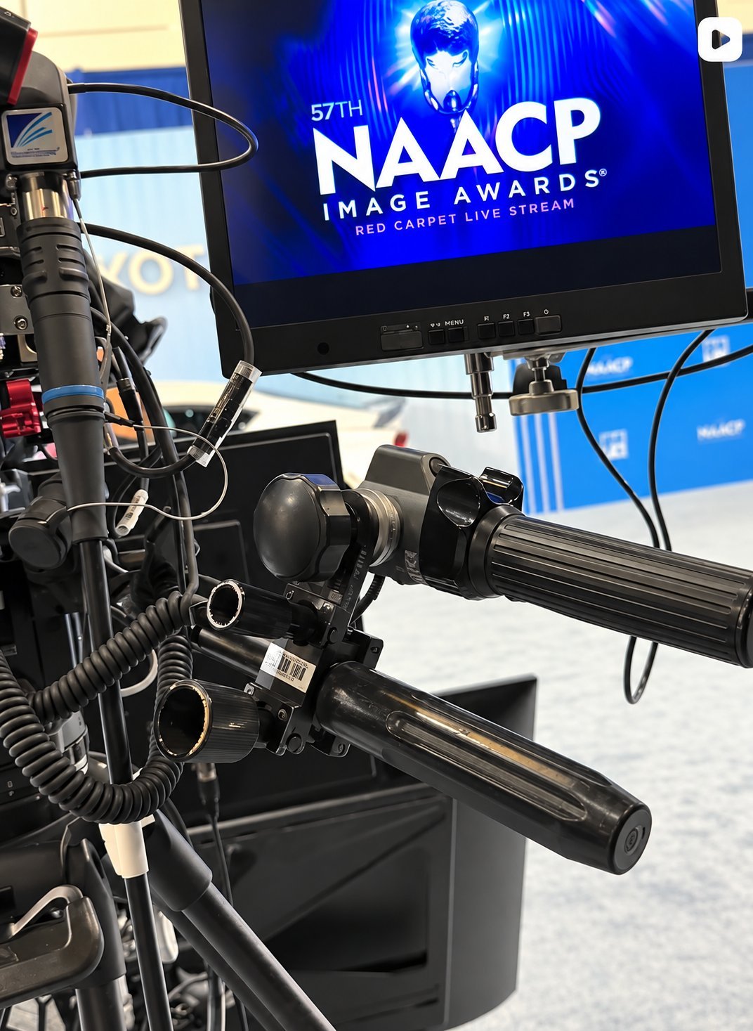 Professional microphone and broadcast camera setup with 57th NAACP Image Awards Red Carpet Live Stream displayed on monitor